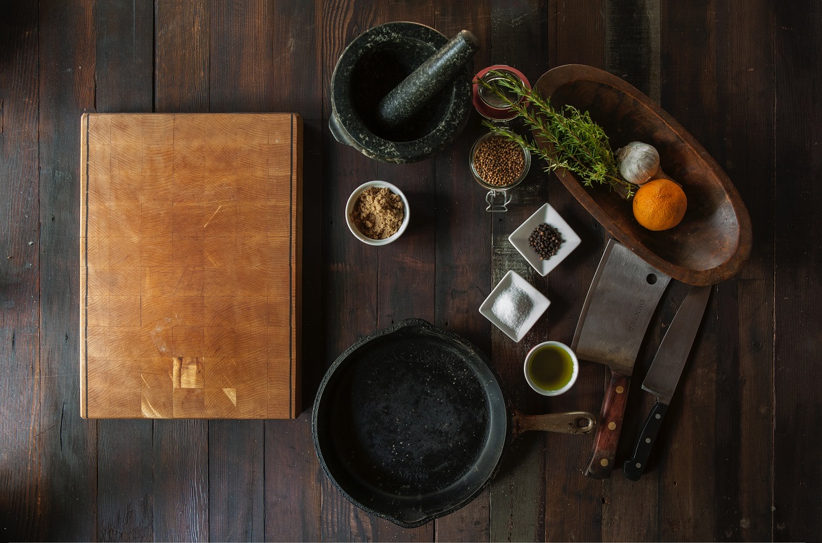 flatlay of kitchen ingredients and pans on a dark wood surface