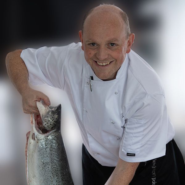 chef spencer westcott holding a salmon and smiling