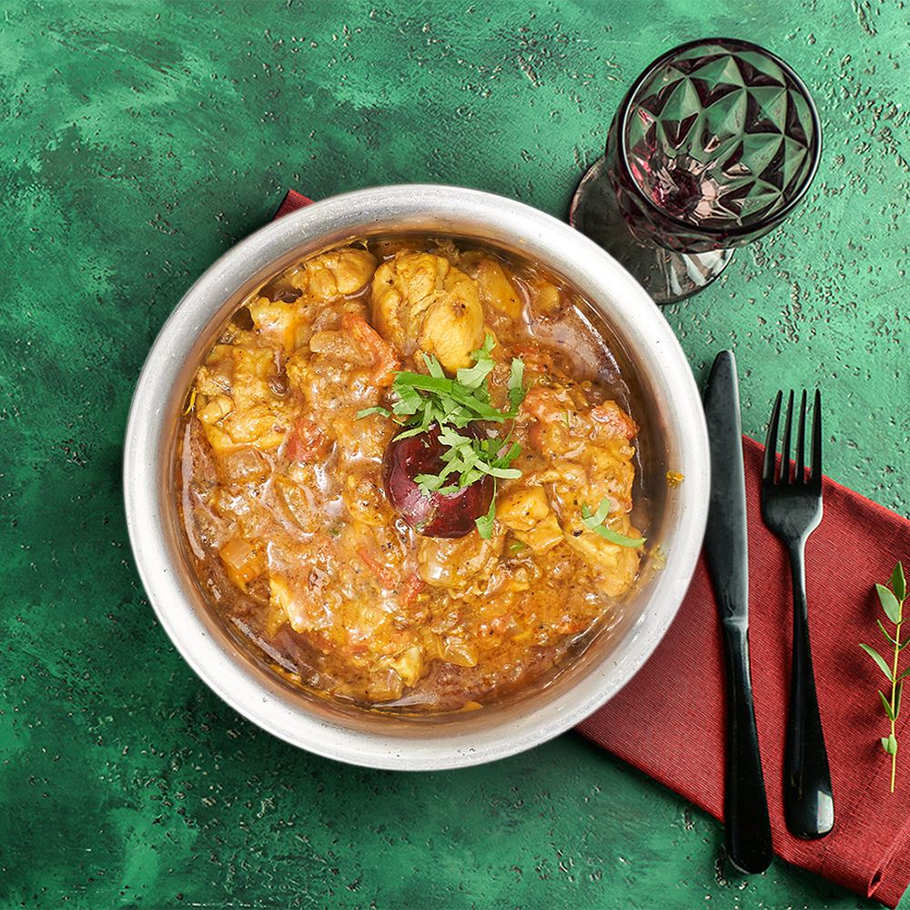 Indian chicken curry in a bowl on a green tablecloth