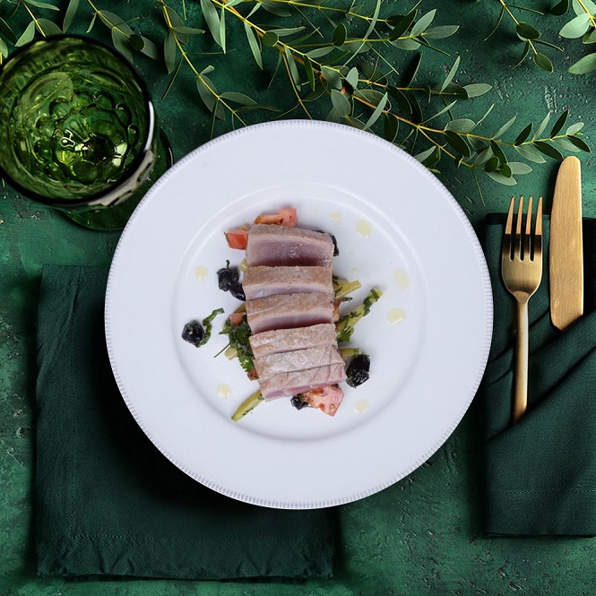 tuna loin steak recipe on a plate with gold cutlery and green tablecloth