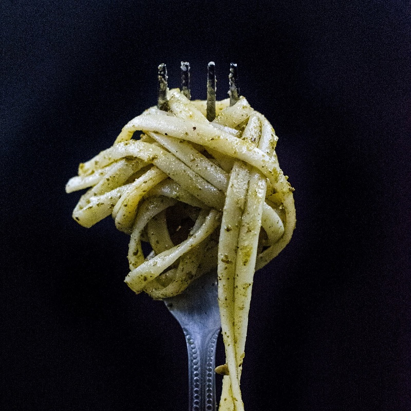 italian national dish cacio e pepe pasta twirled around a fork on a black background