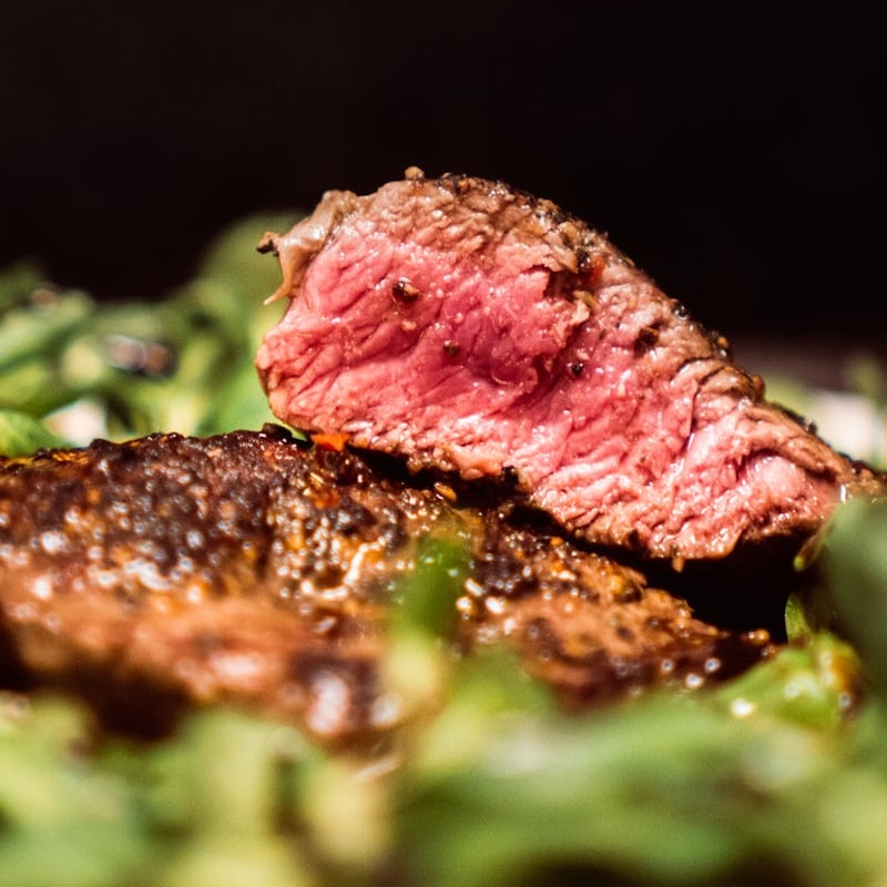 close up image of medium rare belgian steak with greens