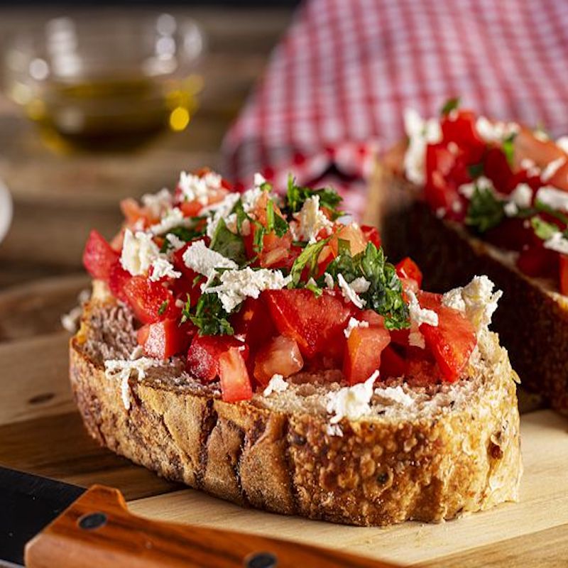 vegan bruschetta on a wooden table with tomatoes and vegan cheese