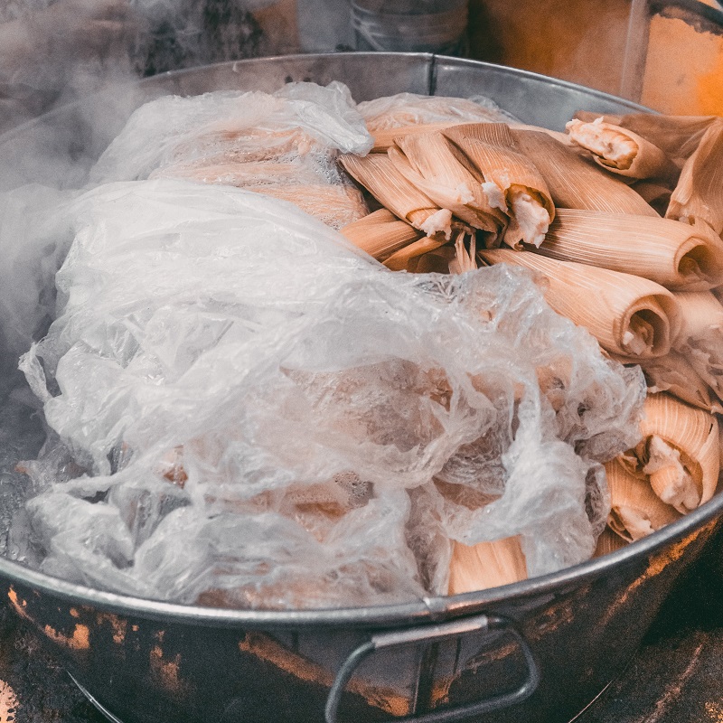 tamales cooking in a large pan on a street in mexico