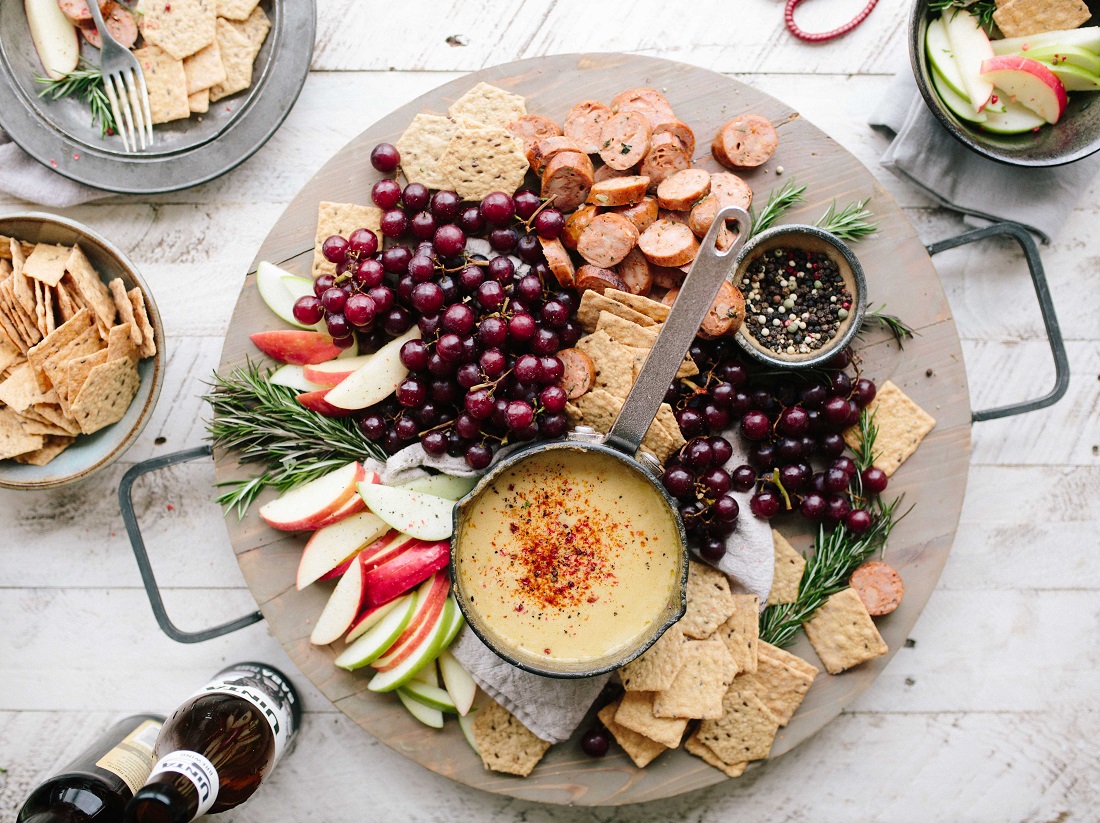 a loaded cheese board seen from above with dips crackers and fruit