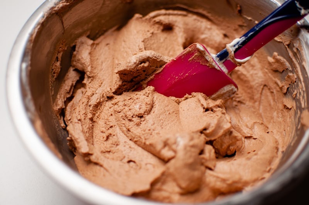 Brownie batter in metal bowl with red spatula