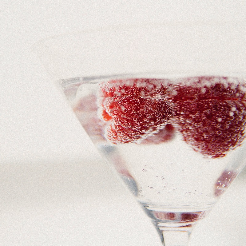 raspberry fizz cocktail with sparkling wine in a martini glass with fresh raspberries