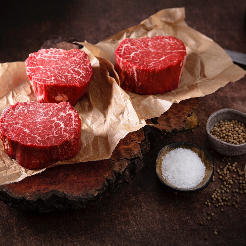 3 beef steaks on baking paper with salt and spices