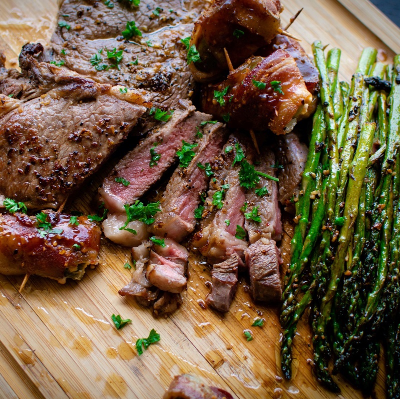 cooked steak on a wooden chopping board with asparagus