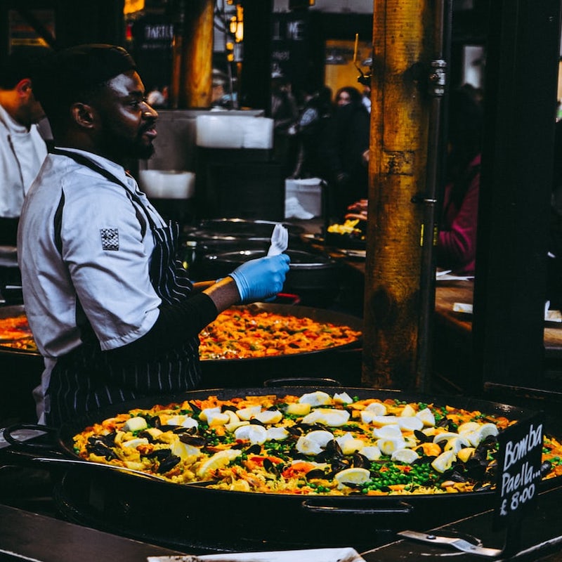 vegan paella in a market with chef standing behind