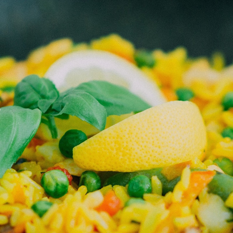 close up of lemon wedge on top of vegan paella dish
