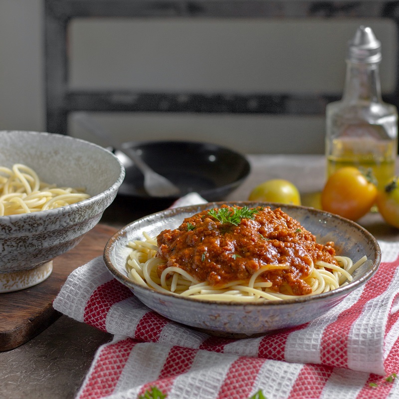 bowl of spaghetti bolognese on a red and white tablecloth