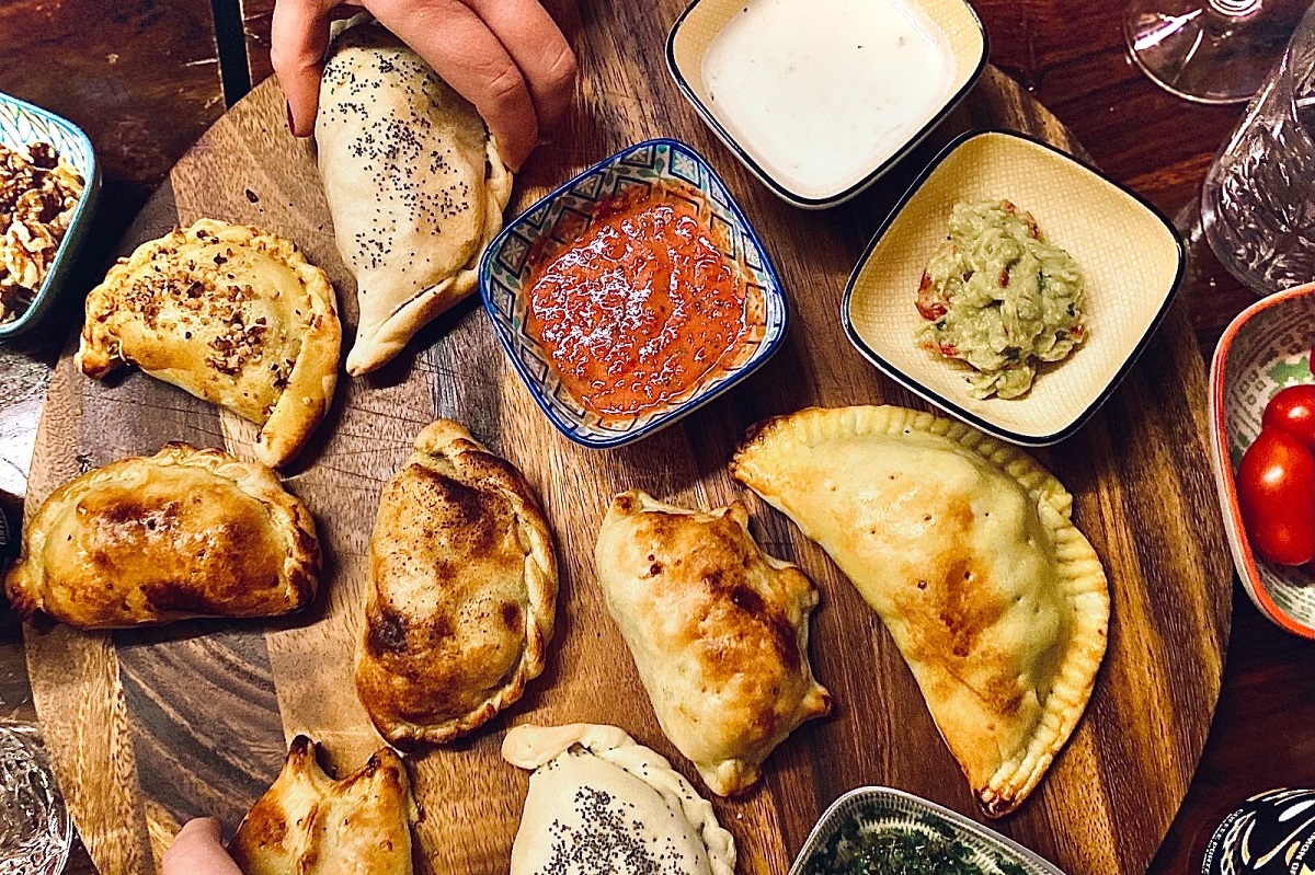 spanish food for kids spread out across a table with hands reaching to grab tapas dishes