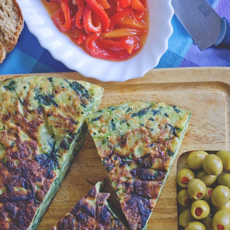 spanish tortilla omelette on a wooden chopping board with olives