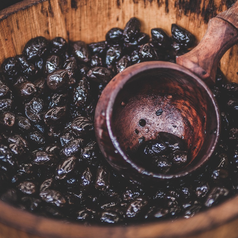 close up of a wooden barrel filled with spanish black olives