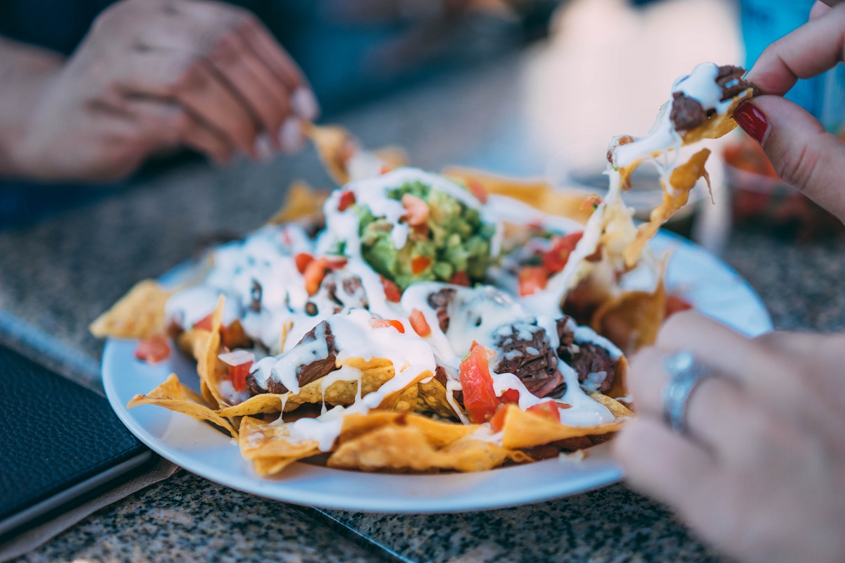 friends enjoying a plate of loaded nachos around a table