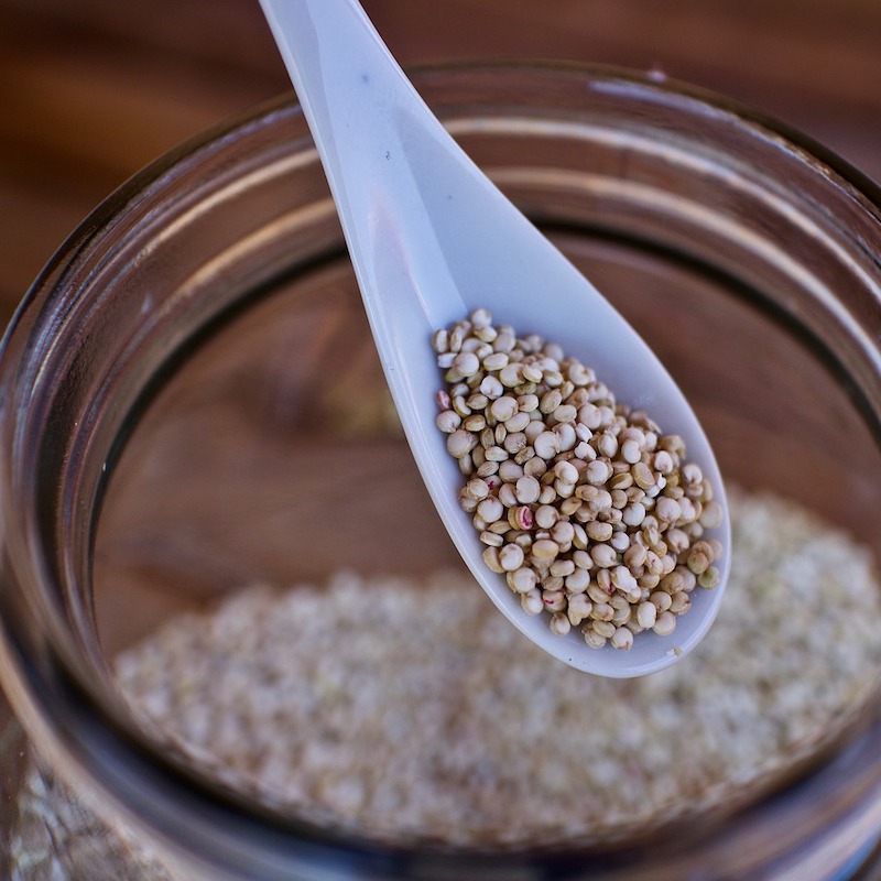 spoon of raw quinoa taken out of a jar