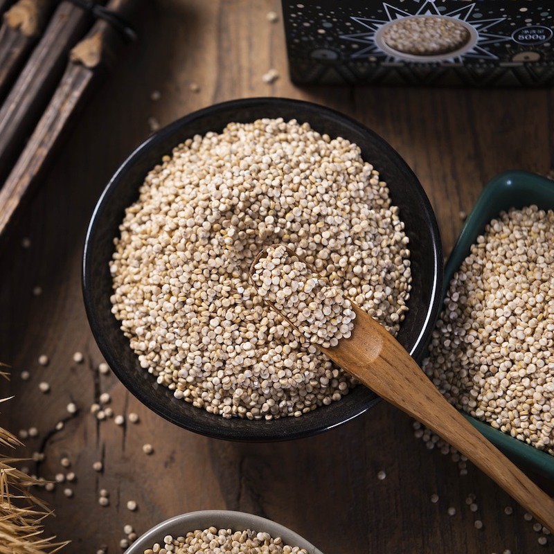 bowl of uncooked quinoa with a wooden spoon