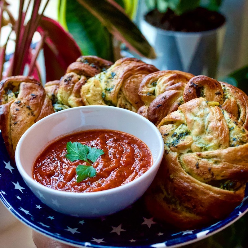 Twisted vegan garlic bread with herbs and a bowl of tomato marinara sauce