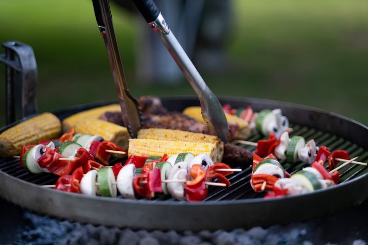 corn on the cob and vegetables cooking on a bbq grill
