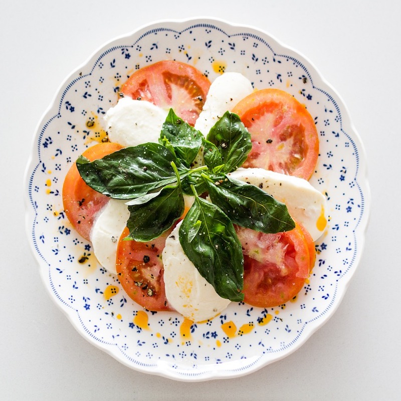 caprese salad on a plate with fresh basil leaves