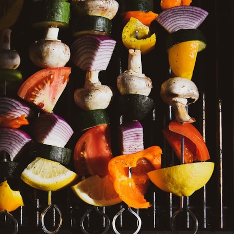 mixed vegetables on skewers cooking on a bbq