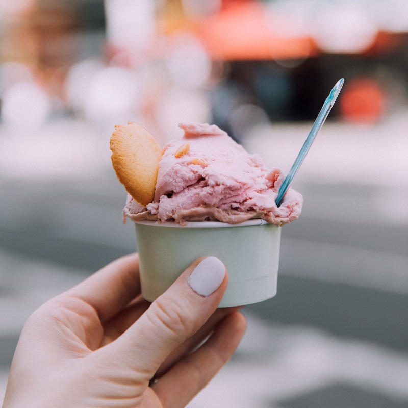 strawberry gelato recipe in a cup with a biscuit being held up by a hand
