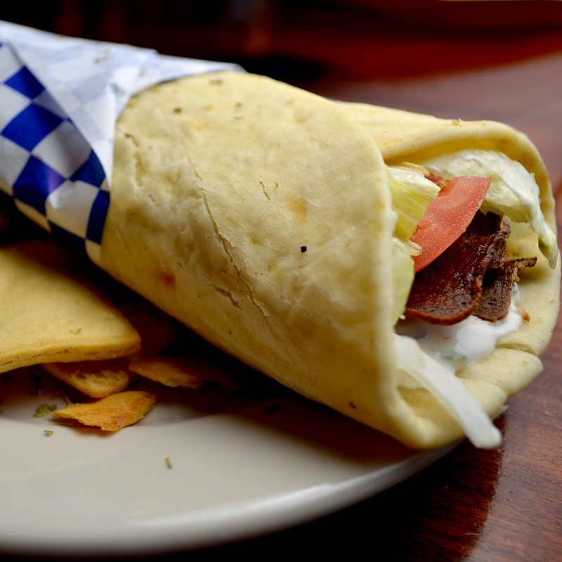 greek gyro pita sandwich on a plate with white and blue napkin