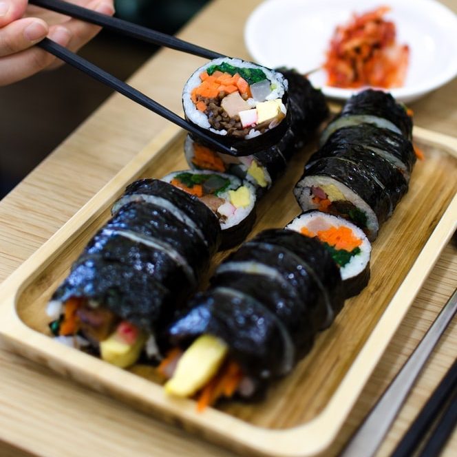 korean gimbap on a wooden plate with chopsticks