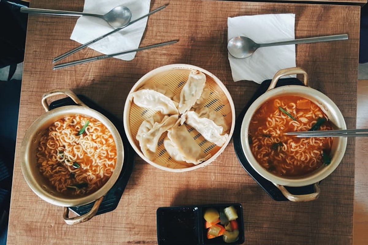 korean noodles in bowls with dumplings on a wooden table