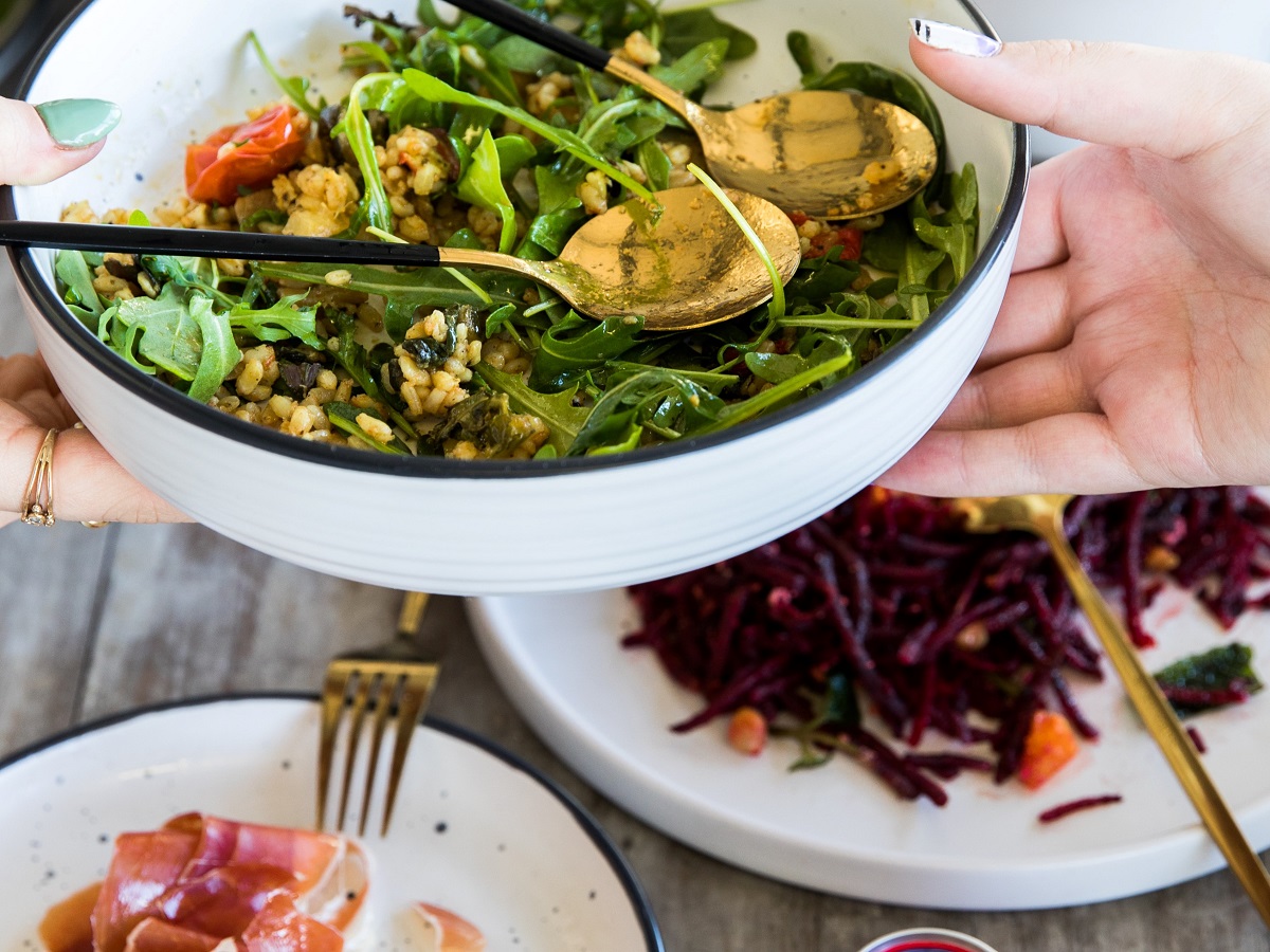 hands passing a bowl of salad across a table at a family dinner