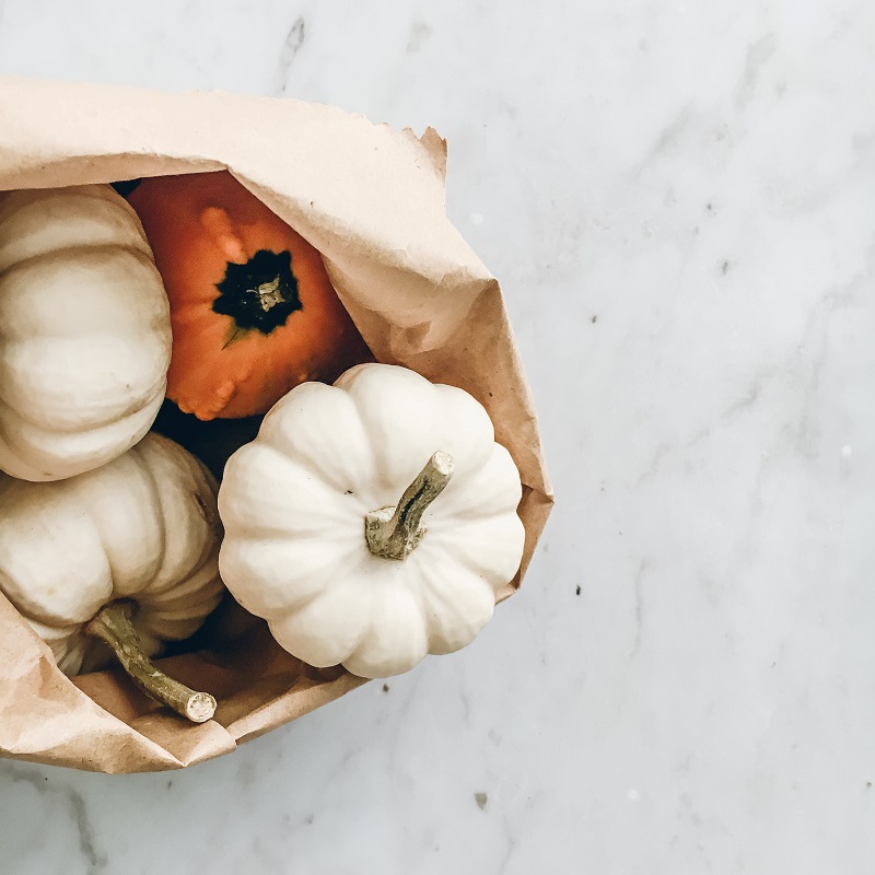 bag of coloured pumpkins on a white marble background