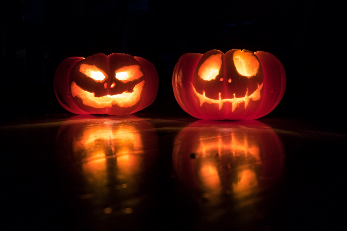two halloween pumpkins lit up in a dark room with scary faces