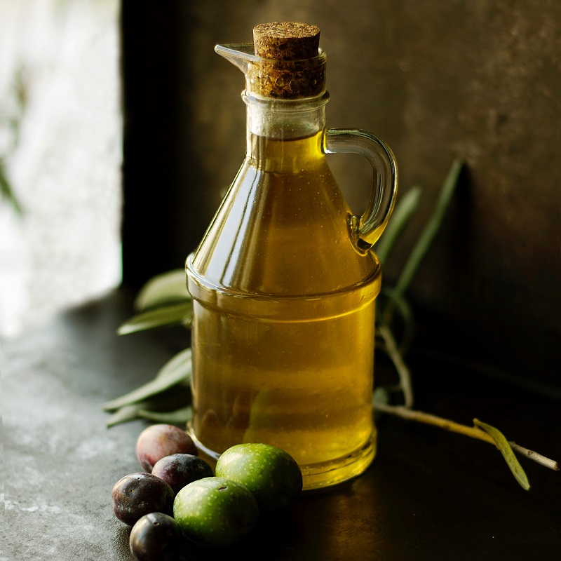 bottle of italian olive oil in a dark room with olives