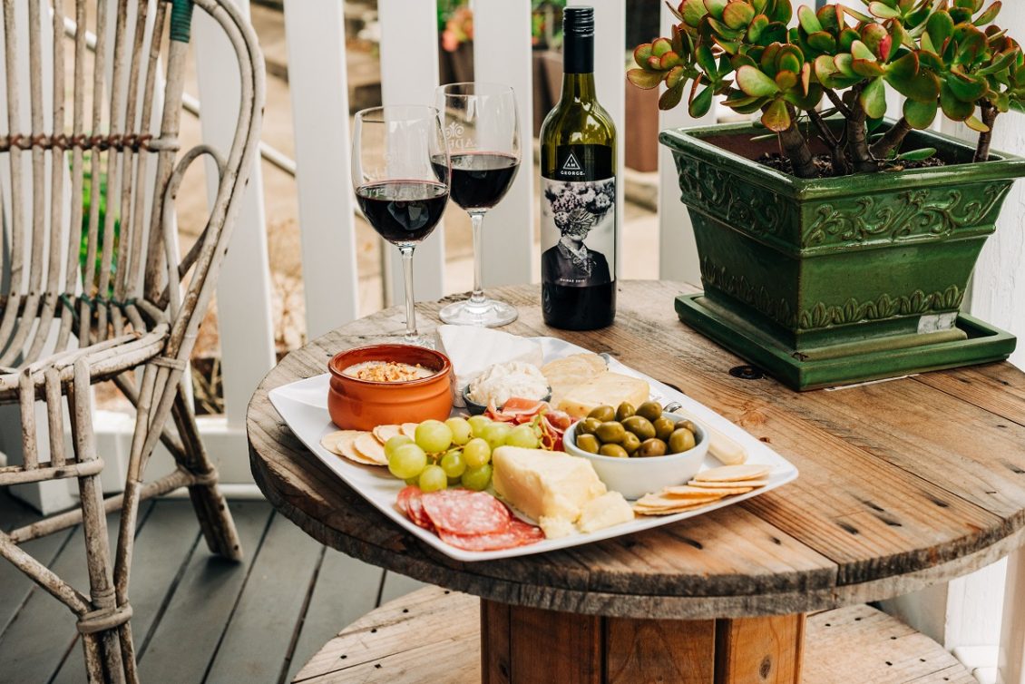 spanish cheese board platter in a garden with glasses of red wine