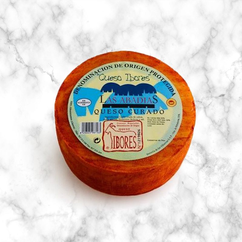 spanish ibores cheese with paprika on a white marble background